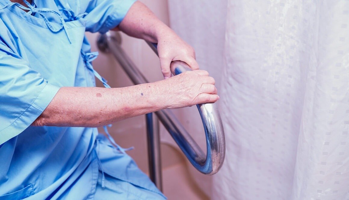 Hands gripping a safety bar in a bathroom.