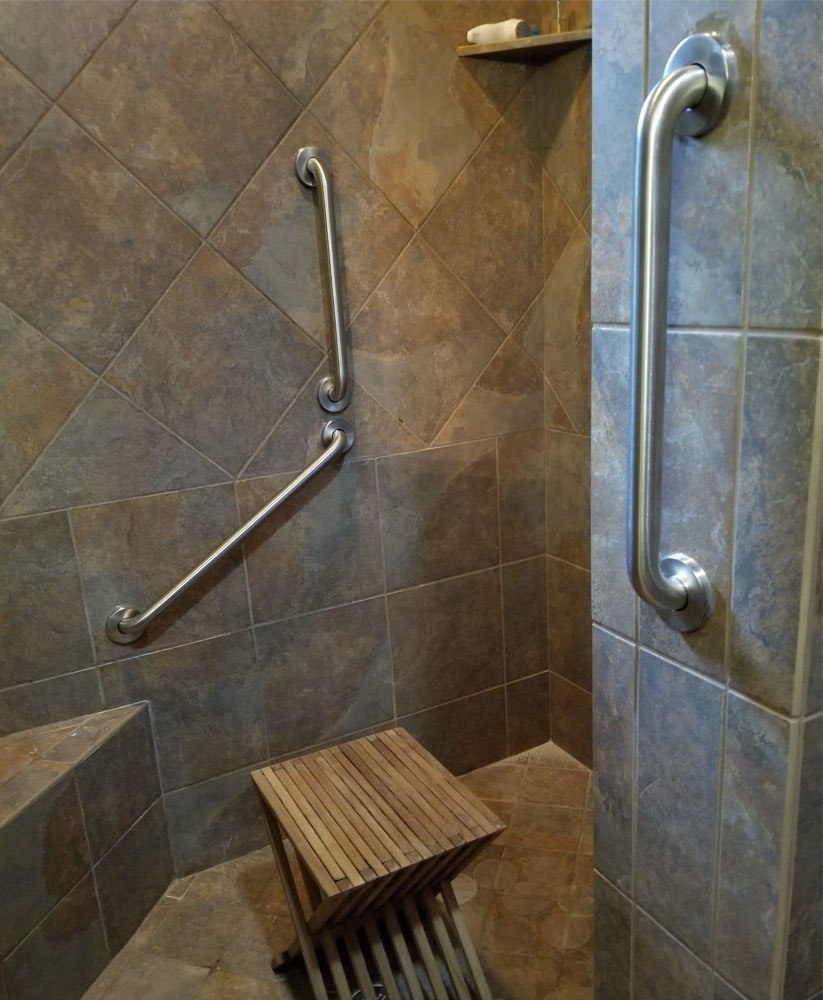 Accessible shower with grab bars and wooden stool.