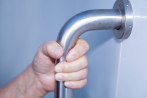 Hand gripping a metallic grab bar.