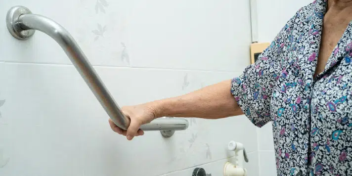 Hand holding a bathroom grab bar for support.