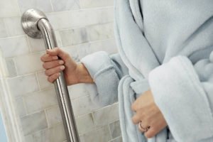 Person in blue robe holding shower grab bar
