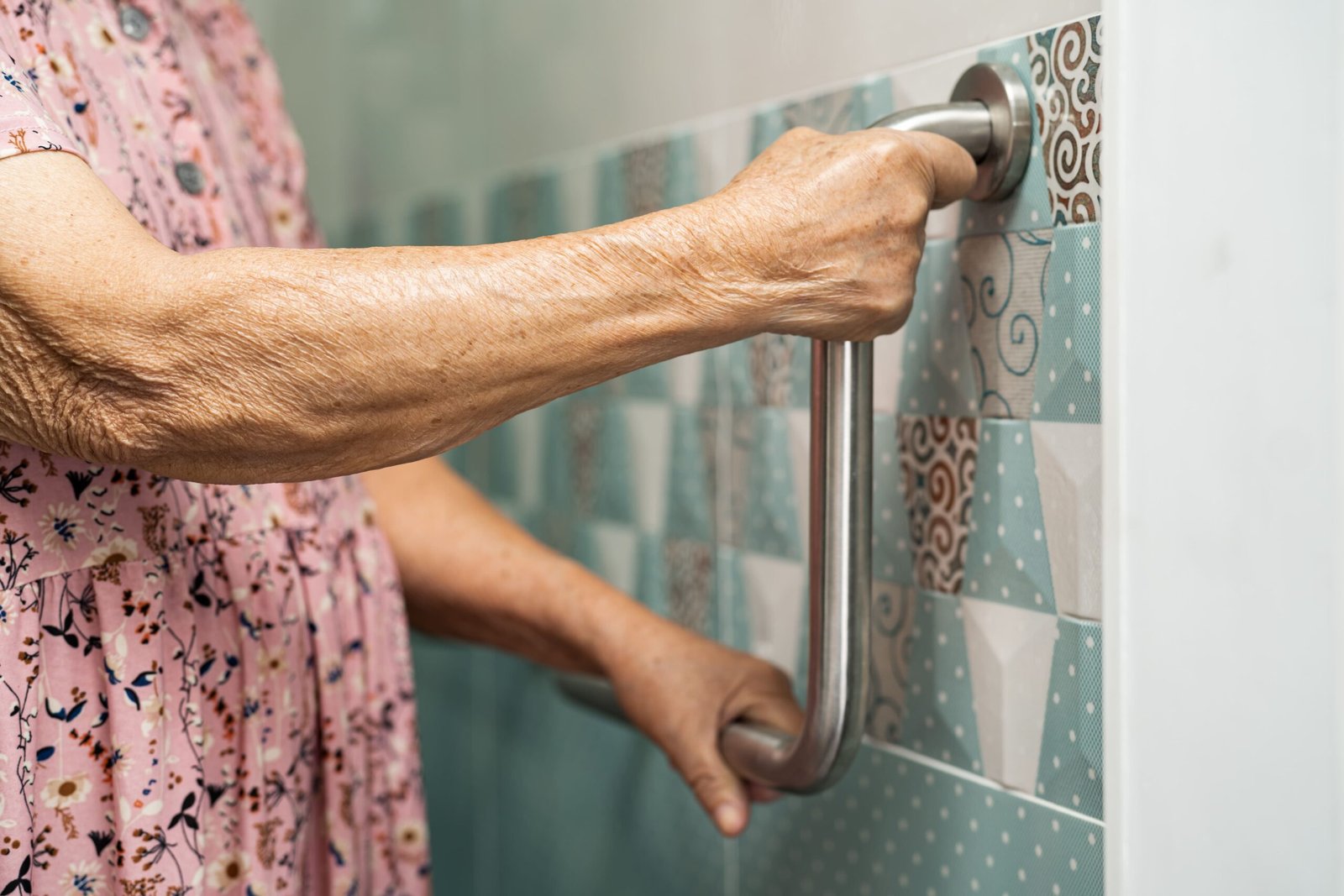 Hand gripping a bathroom safety grab bar