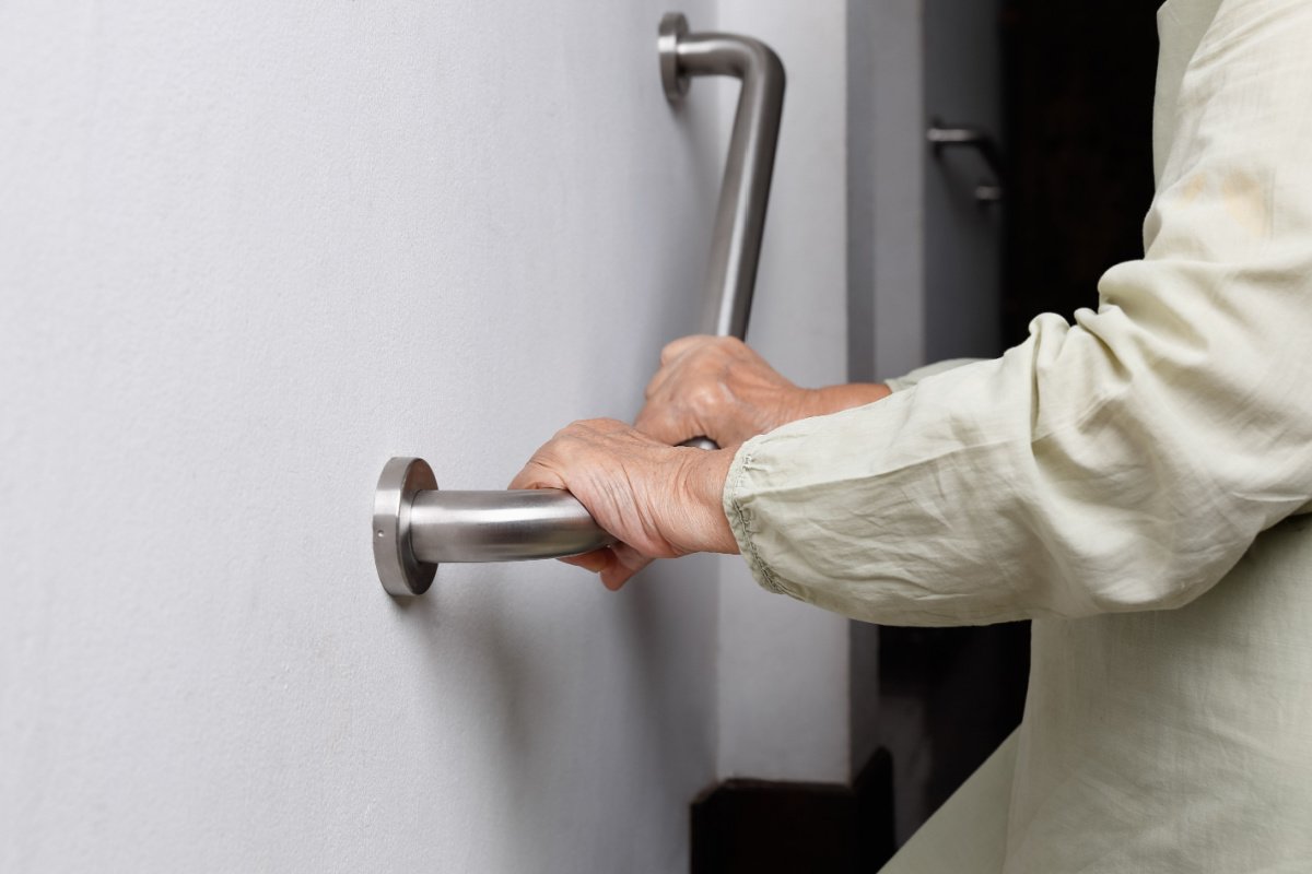Hands gripping a metal grab bar for support.