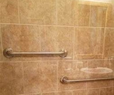 Bathroom wall with grab bars and light reflection.