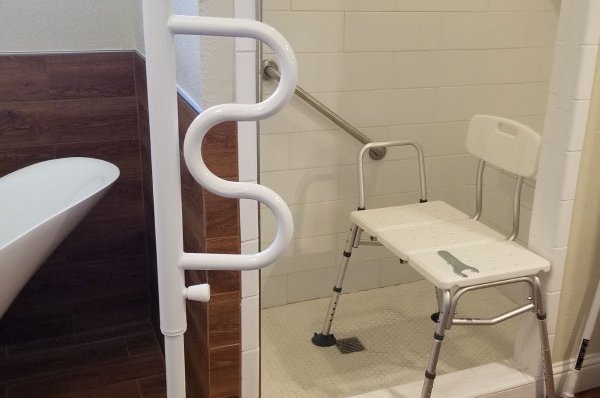 Accessible shower with grab bar and portable chair.