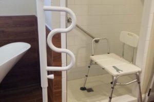 Accessible shower area with grab bars and chair.