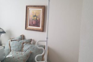 Bed with assistive pole and decorative pillows.