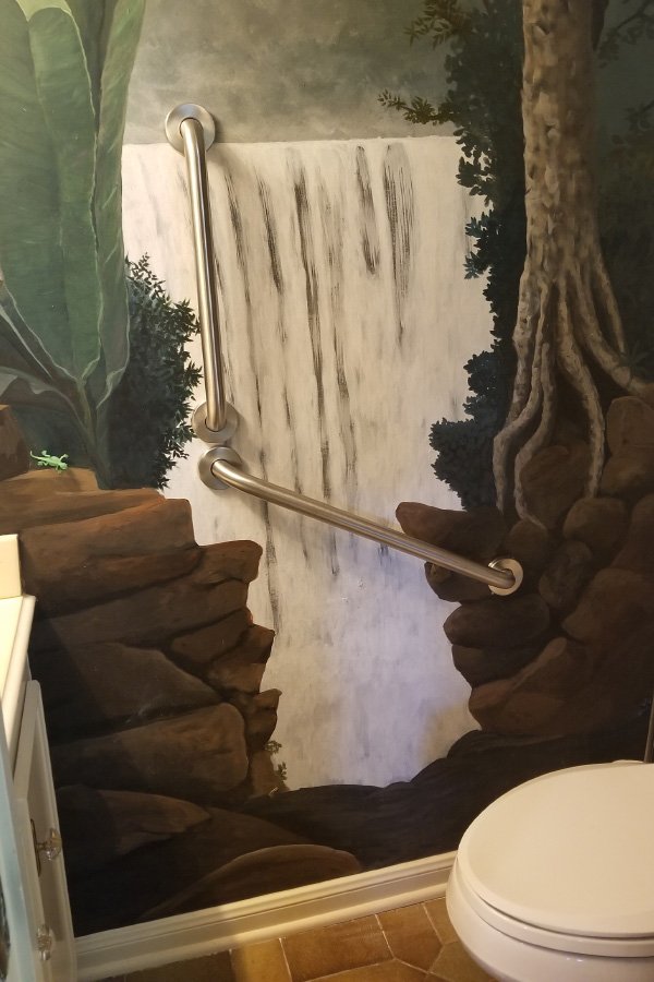 Bathroom with waterfall mural and grab bar.