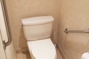 Clean restroom with white toilet and grab bar.